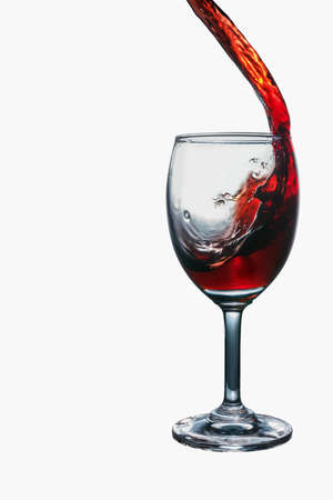 Red wine splash into glass isolated on white background.の写真素材