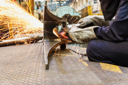 Welder used grinding stone on steel in factory with sparks