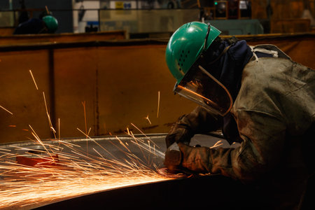 Welder used grinding stone on steel in factory with sparks