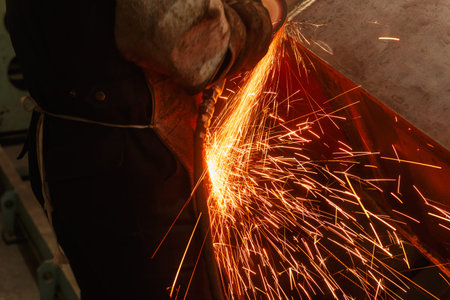 Welder used grinding stone on steel in factory with sparks