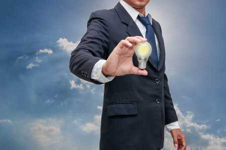 Businessman with holding light bulb on sky background ,In  concept alternative energy from nature