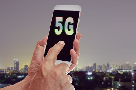 Hand holding mobile smart phone with cityscape,5G network interface