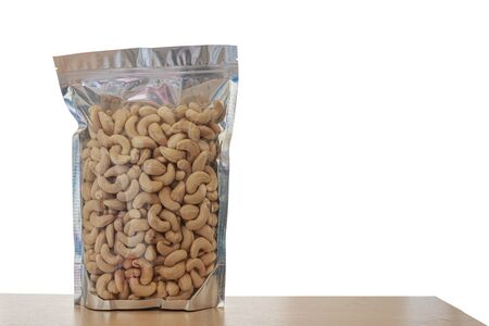 Cashew nuts In the packaging bag with isolated white background  on floor woodの写真素材