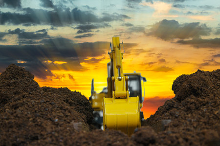 Excavators are digging the soil in the construction site on the sunset background