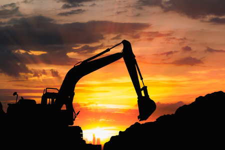 Silhouette of excavator loader  in the construction site on the sky sunset with cityscapes...