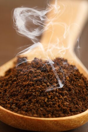 Roasted coffee beans ground on a wooden spoon.の写真素材