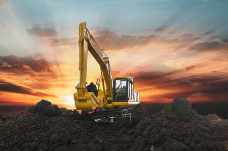 Excavators are digging the soil in the construction site on the  yellow sky sunset  background