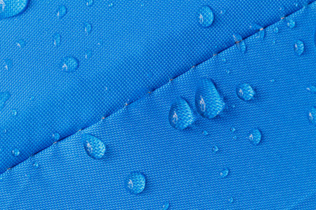 Rain droplets on a blue waterproof fabric  background