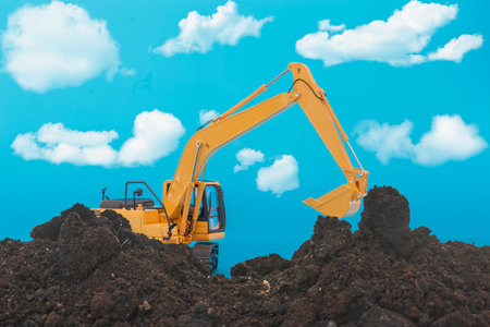Yellow excavators are digging the soil in the construction site on the cloud and  sky  backgroundの写真素材