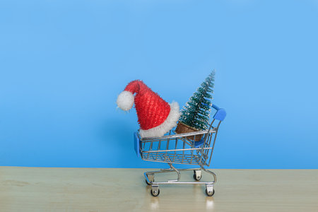 Christmas tree and red hat lie in a shopping trolley ,With  on blue backgroundの写真素材