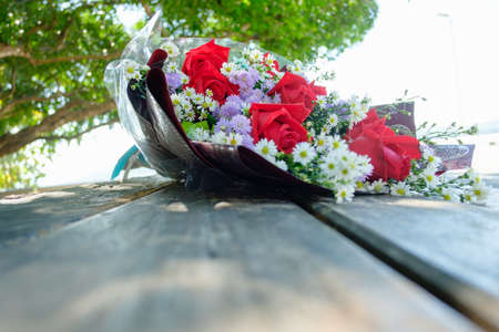 Close up of red roses in a bouquet that has white cutters and purple daisy included. on floor wooden background ,With copy spaceの写真素材