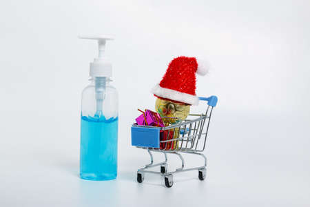 Alcohol gel and Red hat on ball  in a shopping trolley with white backgroundの写真素材