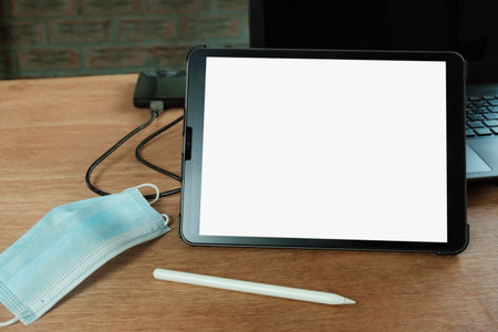 Medical mask and Digital tablet white blank screen display with pen on table  work form home