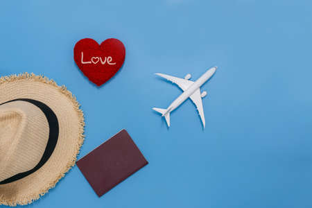 Summer holiday blue background with red heart shape  ,straw hat, passport, Concept of travel by plane in valentines day,  Top viewの写真素材