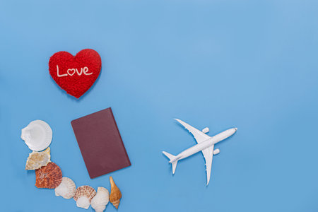 Holiday blue background with red heart shape  ,seashells, passport, Concept of travel by plane in...
