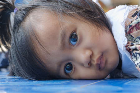 Portrait of an asian baby girl Lying on the floor at homeの写真素材