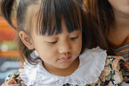 Portrait of an asian baby girl cute and mom with sitting at homeの写真素材