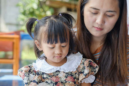 Portrait of an asian baby girl cute and mom with sitting at homeの写真素材