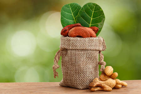 Cashew nuts with green leaf in bag on floor wooden and nature backgroundの写真素材
