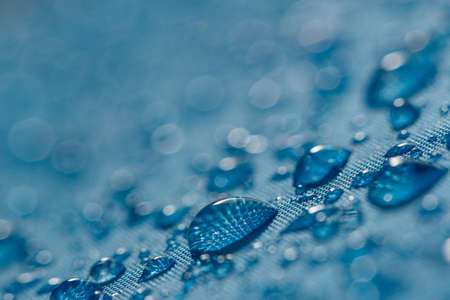 Rain droplets on a blue waterproof fabric  background,close upの写真素材