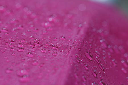 Rain droplets on a magentas waterproof fabric  background,close upの写真素材