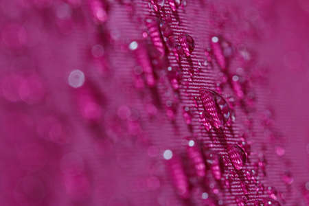 Rain droplets on a magentas waterproof fabric  background,close upの写真素材