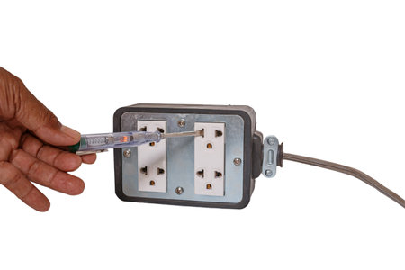 Hand holding a screwdriver to check the voltage electric current in  the power socket. on white...
