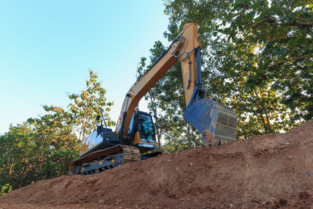 Excavators are digging the soil in the construction site with the tree and  outdoor background