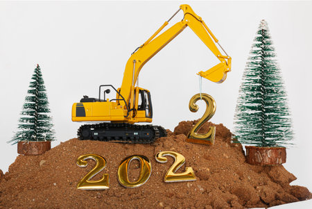 Concept Happy new year 2022,excavator of lift up bucket that is installing the number two letters in construction site with christmas treeの写真素材