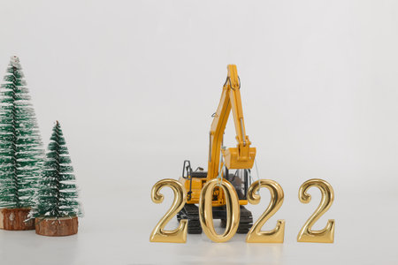 Concept  new year 2022,excavator of lift up bucket that is installing the number zero , two letters in Festival and christmas tree on white backgroundの写真素材
