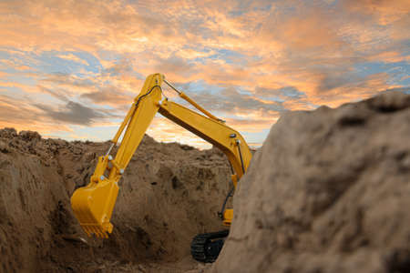 Selective focus ,Excavator with Bucket  are digging canalize the soil in the construction site on the sky backgroundの写真素材