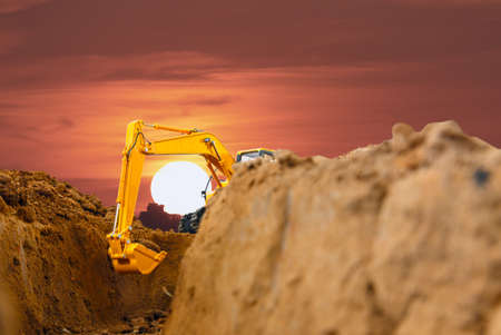 Selective focus ,Excavator with Bucket  are digging  soil in the construction site on the sunset  backgroundの写真素材
