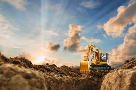 Excavator with Bucket lift up are digging  soil in the construction site on the blue sky and sunset  backgroundの写真素材