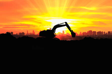 Excavators are digging the soil in the construction site on the sunset backgroundの写真素材