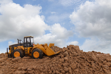 Wheel loader are digging the soil in the construction site on sky background ,with white fluffy...