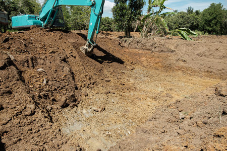 Excavators are digging the soil ,dig a pond in the construction site location fieldの写真素材