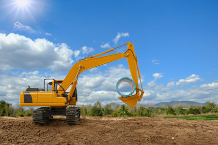Crawler excavators are digging soil at construction site and laying pipe. with clouds and blue sky backgrounds.の写真素材