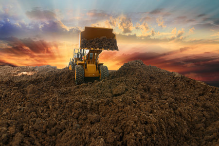 Wheel loader are digging the soil in construction site  on sunset background,with bucket lift upの写真素材
