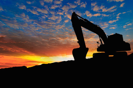 Crawler excavators silhouette are digging the soil in the construction site on the sunset backgroundの写真素材