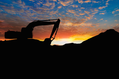 Crawler excavators silhouette are digging the soil in the construction site on the sunset background