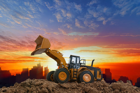 Wheel loader are digging the soil in the construction site on the  sunset background,In city