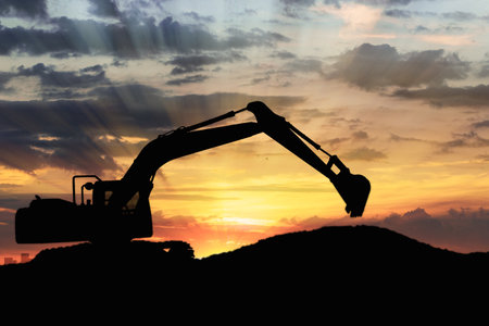 Crawler excavators silhouette are digging the soil in the construction site with bucket lift up. on  sunset  backgroundの写真素材