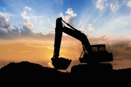 Crawler excavators silhouette are digging the soil in the construction site. With blue sky and clouds of on sunset backgroundの写真素材