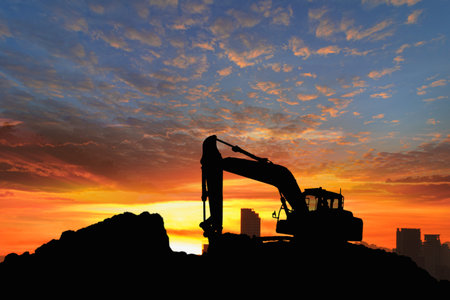 Crawler excavators silhouette are digging the soil in the construction site. With blue sky and...