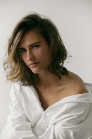 Portrait of beautiful young woman with brown hair and clean bronze skin without makeup on white...