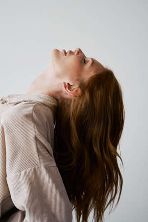 Portrait of young amazing redhead girl in beige shirt on neutral background. Long wavy healthy hair. beautiful and fresh. natural beauty. minimalism. soft light. good quality. hair advertisingの写真素材