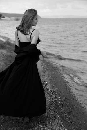 young beautiful girl. Summer landscape, good weather. beach, sea. windy day. Cotton black dress eco style. nature and freedom. Follow me. Long hair, big eyes and lips. black and white photoの写真素材