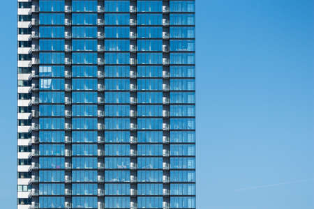 Fragment of a glass skyscraper merged with blue skyの写真素材