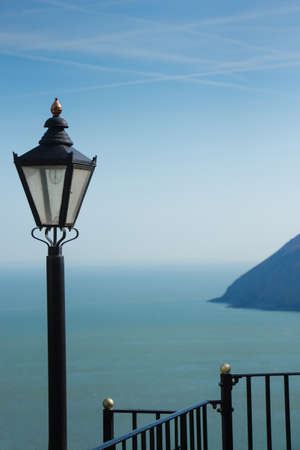 A view of the ocean and the sky merging in a misty horizon, seen from a viewpoint surrounded by railings and decorated with old style street lanternの写真素材