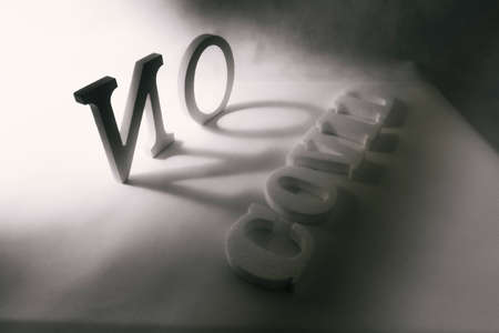 Composition of letters on a white background illuminated from the side with the word Covid-19の写真素材